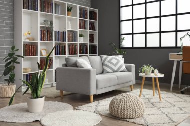 Gri kanepesi ve kitaplığı olan modern oturma odasının içinde.