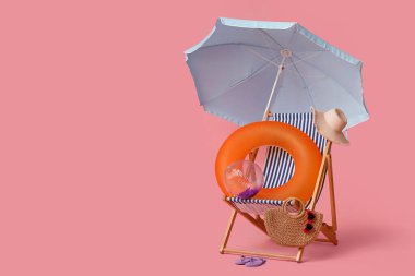 Güverte sandalyesi, plaj şemsiyesi, şapka, hasır çanta, güneş gözlüğü, parmak arası terlik, şişirilebilir yüzük ve pembe arka planda top.