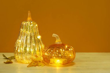 Sonbahar yapraklı, turuncu arka planda parlayan balkabakları.