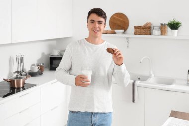 Mutfakta bir bardak süt ve kurabiye olan genç bir adam.