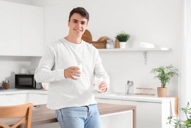 Mutfakta süt bardakları olan genç bir adam.