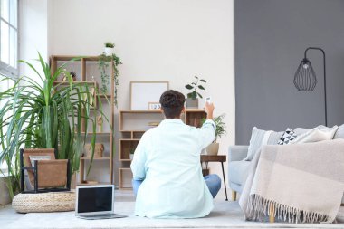 Delikanlının evdeki klimayı açması, arka manzara