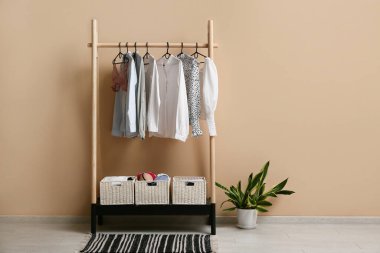 Odada bej duvarın yanında kadın kıyafetleri ve iç çamaşırları var.