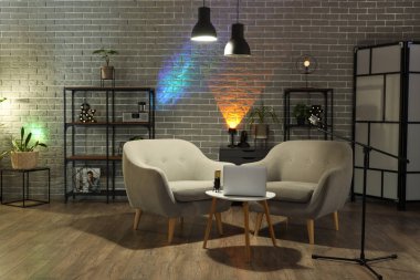 Podcaster 'ın iş yeri, raf üniteleri ve parlayan lambaları olan karanlık stüdyonun içi.