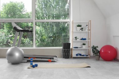 Raf ünitesi, koşu bandı ve spor ekipmanlarıyla hafif spor salonu.