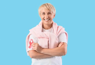 Mavi arka planda pembe kurdeleli olgun bir kadın. Göğüs kanseri farkındalığı konsepti
