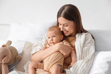 Mutlu anne yatak odasında bebeğine sarılıyor.