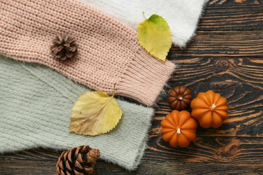 Tahta arka planda sıcak süveterler, mumlar ve çam kozalakları olan kompozisyon, yakın plan.