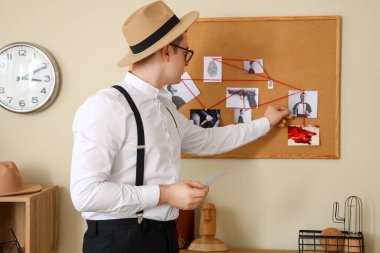 Male detective investigating case near crime board in office clipart