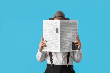 Erkek dedektif mavi arka planda gazete okuyor.