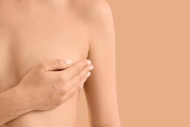 Bej arka planda çıplak bir kadın, yakın plan. Göğüs kanseri farkındalığı konsepti