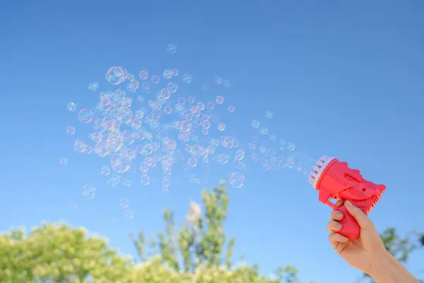 stock image Female hand with soap bubble gun on blue sky background