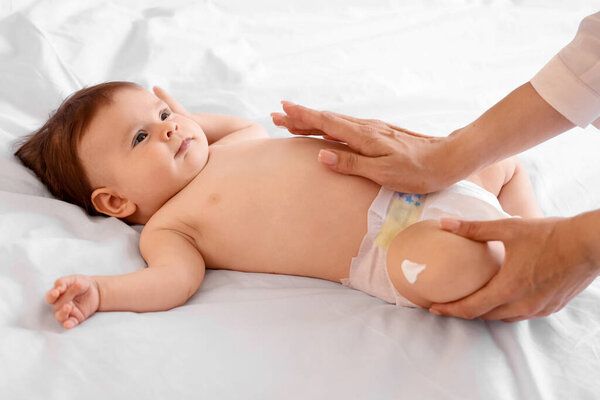 Мама наносила крем на ногу малыша в спальне, крупным планом