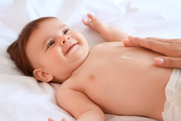 Мама наносила крем на живот своего малыша в спальне, крупным планом