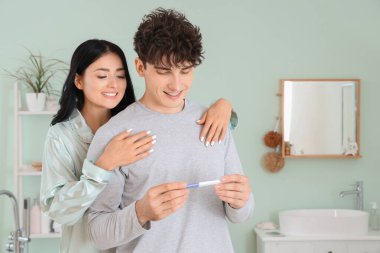Banyoda hamilelik testi olan mutlu genç bir çift.