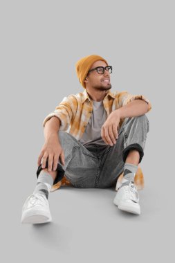 Spor ayakkabılı genç adam arka planda oturuyor.