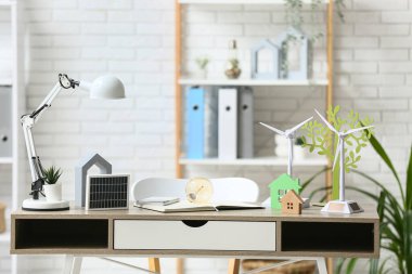 Ampul, ev figürleri ve güneş paneli olan rüzgar türbini modelleri ofiste. Yeşil Enerji kavramı