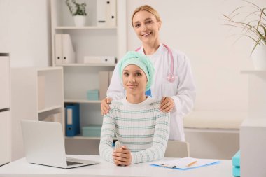 Kemoterapiden sonra klinikte doktorla gülümseyen genç bir kadın.