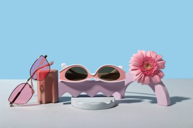 Süslü güneş gözlüklü dekoratif podyumlar ve renkli arka planda Gerbera çiçekleri
