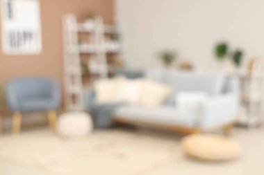 Gri kanepe, koltuk ve raf üniteleriyle şık oturma odasının bulanık görüntüsü