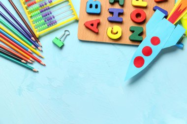 Abaküslü renkli kağıt roket, ahşap harfler ve renkli arka planda kalemler.