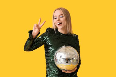 Disko toplu güzel genç bir kadın sarı arka planda zafer jesti gösteriyor.