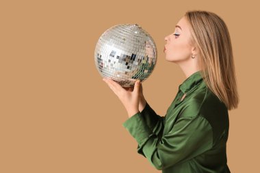 Kahverengi arka planda öpücükler saçan disko toplu güzel genç bir kadın.