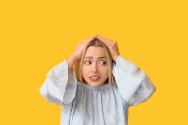 Young woman feeling shame on yellow background clipart