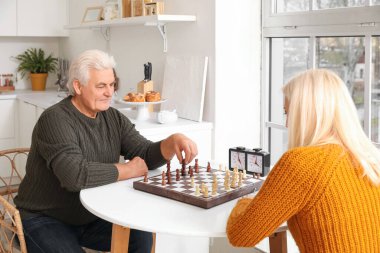 Olgun bir adam ve karısı mutfakta satranç oynuyorlar.