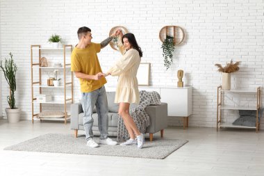 Mutlu genç çift evde dans ediyor.