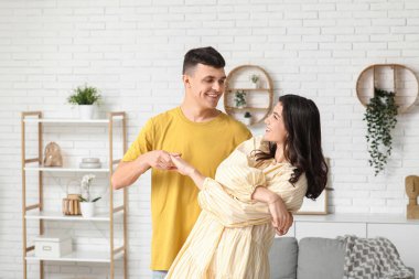 Mutlu genç çift evde dans ediyor.