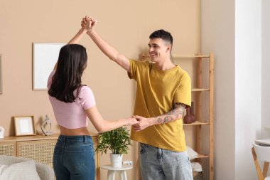 Güzel, genç bir çift oturma odasında dans ediyor.