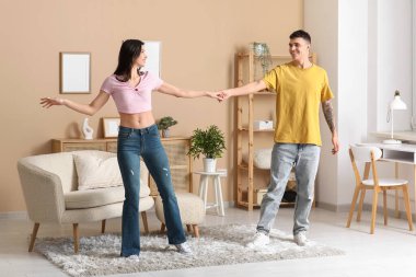 Oturma odasında dans eden mutlu genç çift.