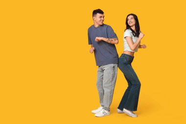 Sarı arka planda dans eden mutlu genç çift