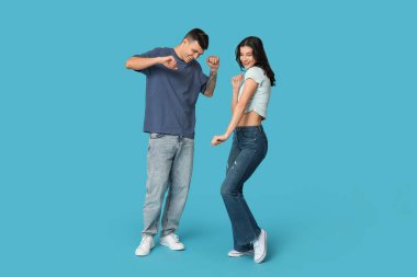 Mavi arka planda dans eden mutlu genç çift