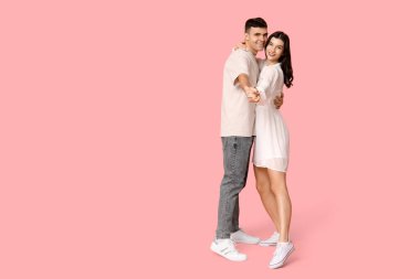 Pembe arka planda dans eden güzel genç çift