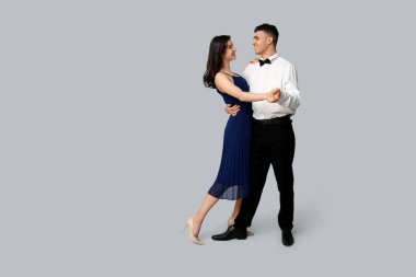 Gri arka planda dans eden güzel genç çift