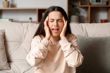 Evde şiddetli baş ağrısı çeken genç bir kadın.