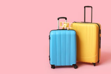 Pembe arka planda bavullar ve oyuncak uçak. Seyahat kavramı