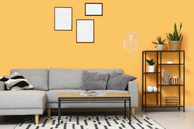 Güzel oturma odasının içinde rahat bir kanepe, halı, raf ünitesi ve kahve masası var.