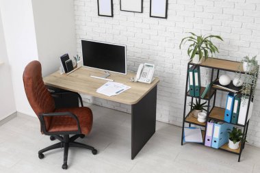 Çalışma yeri, koltuğu, modern bilgisayarı ve raf ünitesi olan şık bir ofis.