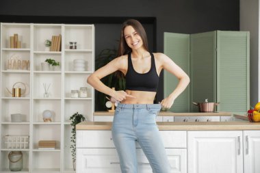 Güzel, genç ve mutlu bir kadın evdeki bol kotları işaret ediyor. Kilo verme konsepti
