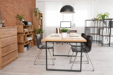 Çalışma alanları, sandalyeleri ve raf ünitesi olan modern açık uzay ofisi.