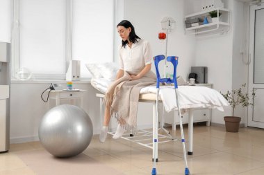 Hastane koğuşunda yatağında oturan kadın hasta.