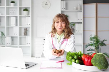Ofisteki masada kivi yiyen kadın beslenme uzmanı.