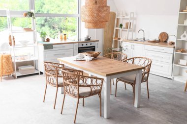 Mutfağın içinde yemek masası, tezgah ve raf üniteleri var.