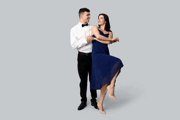 Счастливая молодая пара танцует на сером фоне