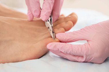 Güzellik uzmanı, kaplıca salonundaki kanepede ayak tırnaklarını kesiyor.