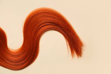 Bej arka planda kırmızı saç teli, yakın plan.