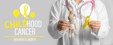 Oyuncak ve arka planda altın kurdeleli bir doktor. Çocukluk Kanseri Farkındalığı Ayı